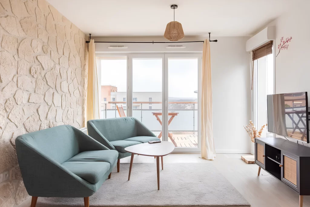 Salon lumineux de la colocation FlatZen à Cergy-le-Haut avec fauteuils et accès balcon